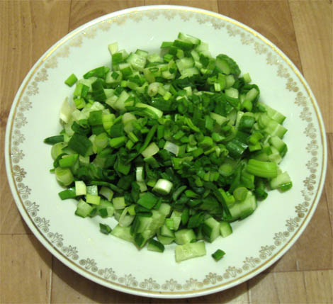 Нарезанные огурцы и покрошенный зелёный лук на тарелке